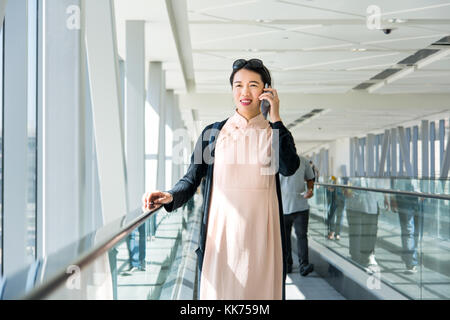 Ragazza con telefono mentre sul tapis roulant all'interno Foto Stock