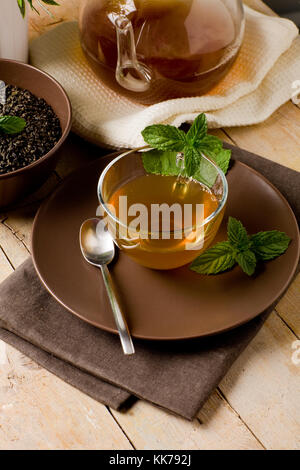 Foto di verde delizioso tè alla menta in coppa di vetro sul tavolo di legno Foto Stock