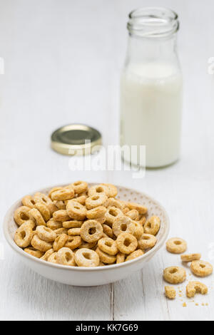 Gli anelli di avena in una ciotola e bottiglia di latte. Foto Stock