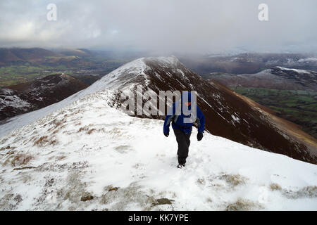 Lone fellwaker maschio su un crinale in direzione wainwright cicatrice dirupi da causey pike nella neve, parco nazionale del distretto dei laghi, cumbria, Regno Unito. Foto Stock