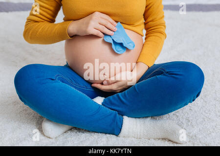 Close up della donna incinta che tiene poco calze Foto Stock