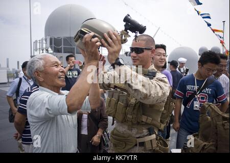 Il personale Sgt Max Veliz, un Marine assegnato alla flotta di sicurezza antiterrorismo Team Fast Company Pacific, terzo plotone, mette un casco su un visitatore durante una nave aperta tour a bordo della US 7 ammiraglia della flotta USS Blue Ridge LCC 19 in Tokyo, Giappone, 2012. Immagine cortesia la comunicazione di massa specialista di terza classe Fidel C. Hart/US Navy. Foto Stock