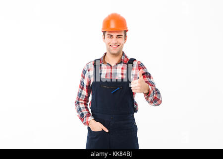 Ritratto di un sorridente giovane maschio builder mostra Thumbs up gesto mentre in piedi e guardando la telecamera isolate su sfondo bianco Foto Stock