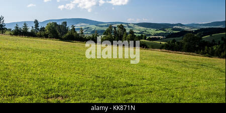 Paesaggio di montagna con prati, campi e villaggi, alberi, colline e cielo blu con nuvole in Boemia - terra di confine moravo vicino a kraliky città in czec Foto Stock