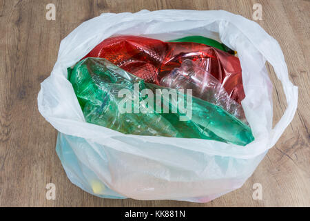 Usato colorato di bottiglie di plastica su uno sfondo di legno. Smaltimento ecologico dei rifiuti domestici. La separazione dei rifiuti. Crumpled wrapper di PET in una borsa di trasporto. Foto Stock