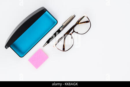 Piatto occhiali laici, sticky appunti e penna di fantasia su sfondo bianco con copia spazio. Foto Stock