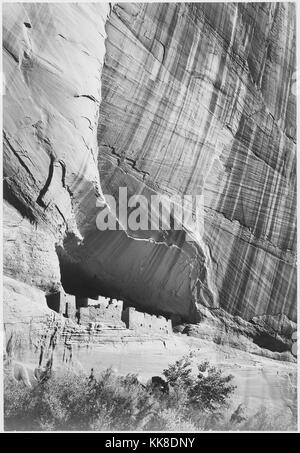 Una fotografia in bianco e nero di un insediamento creato alla base di una scogliera in Canyon De Chelly monumento nazionale, la zona è una delle più antiche in continuo di zone abitate in Nord America, è di proprietà del Navajo Tribal Trust della Navajo Nation ed è gestito in collaborazione con il Parco Nazionale di Servizio, l'immagine proviene da una serie di fotografie noto come il progetto murale di Ansel Adams, fu commissionato dal Servizio del parco nazionale nel 1941 per creare un murale fotografico per il dipartimento dell'interno edificio in Washington DC, il progetto è giunto a termine a causa della Seconda guerra mondiale, Foto Stock