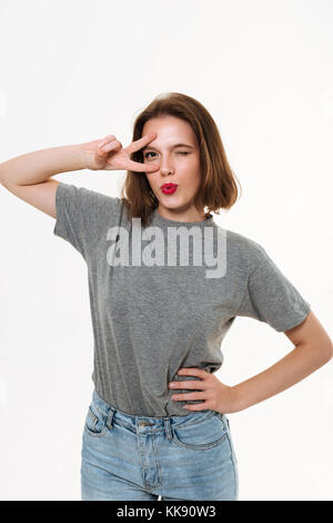 Immagine di piuttosto giovani caucasici permanente lady isolate su sfondo bianco. Guardando la telecamera che mostra graziosi emozioni. Foto Stock