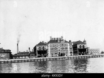 Una fotografia della parte esterna di Ellis Island Ospedale come si vede da tutta l'acqua, l'ospedale fu inaugurato nel 1902 e gestito fino al 1930, fu il primo ospedale pubblico negli Stati Uniti, è stato usato come un centro di detenzione per immigrati che sono state ritenute troppo poco per inserire il paese subito dopo il loro arrivo, se la persona non potrebbe essere induriti sono stati inviati di ritorno al loro paese e altri edifici tra cui porzioni di immigrazione stazione di ispezione e impianto di alimentazione possono essere visti sullo sfondo, New York, 1907. Dalla Biblioteca Pubblica di New York. Foto Stock