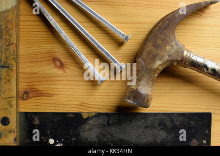 Martello, chiodi e quadrato su sfondo di legno. vista superiore strumenti diy immagine. Foto Stock