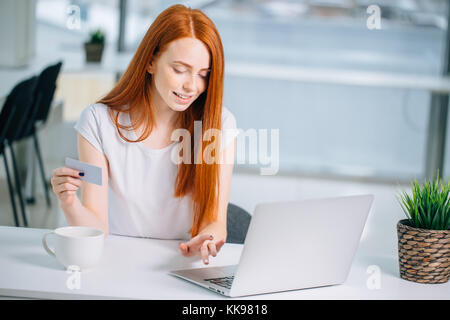 Shopper ragazza acquisto online con un computer portatile e una carta di credito Foto Stock