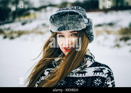 Ritratto di bel giovane donna con occhi blu guardando la fotocamera e indossando cappello caldo d'inverno. Foto Stock