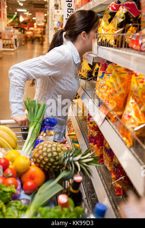 Giovane donna con carrello nel supermercato quando lo shopping | uso in tutto il mondo Foto Stock