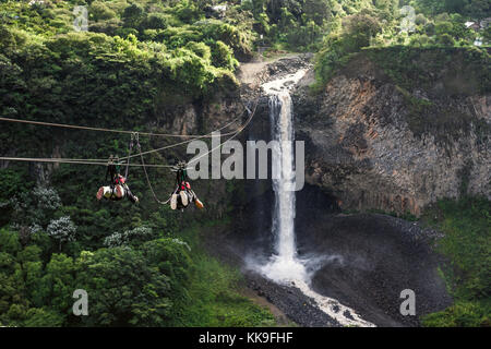 I turisti scorrevolezza su zip line viaggio contro il velo nuziale (manto de la novia), la cascata nel percorso di Cascades, banos, Ecuador Foto Stock