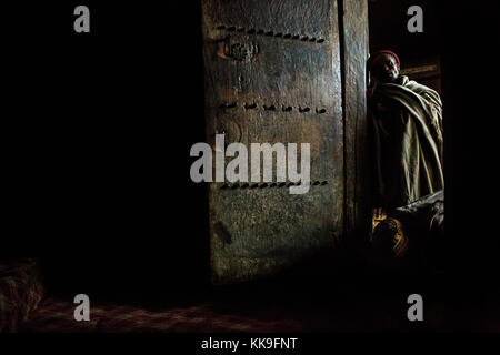 Un uomo religioso permanente al yemrehana krestos chiesa, un impressionante grotta chiesa vicino a Lalibela, Etiopia. Foto Stock