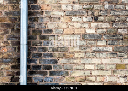 Il vecchio muro di mattoni con tubo di drenaggio Foto Stock