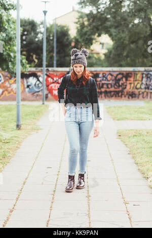 Giovane donna redhead passeggiate all'aperto che guarda lontano sorridenti - sereno, cliente emozioni positive concept Foto Stock