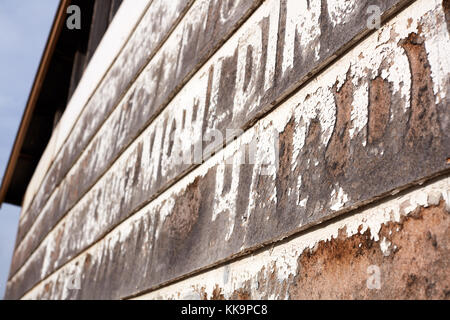 Il vecchio in legno rustico edificio rivestito con i resti del lettering bianco in un vicino fino ad angolo obliquo view Foto Stock
