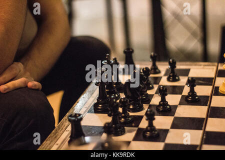 Guy pensare la sua prossima mossa mentre si gioca a scacchi neri Foto Stock