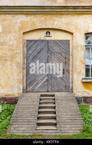 Antica facciata in fabbrica con porte in legno e rampa. vintage Foto Stock