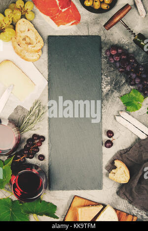 Vista in pianta di un fustellato chalk board per un vino un elenco o menu con vino e snack set. Varietà di formaggio, olive, prosciutto di carne, baguette fette, nero gr Foto Stock