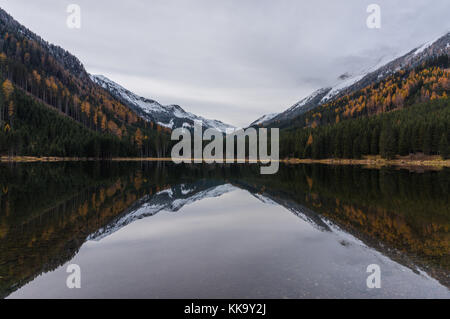 In autunno la foresta colorata e montagne coperte di neve che riflette nelle fredde acque del ingeringsee Foto Stock