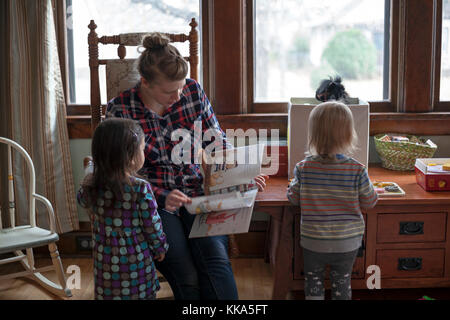 Una madre legge un libro a sua figlia e un amico. Foto Stock