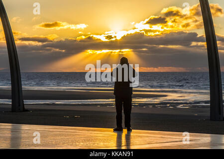 Blackpool, Lancashire, Regno Unito meteo 30 novembre 20117. Sunny fine ad un freddo giorno come un turista per il resort prende una fotografia, dalla commedia marciapiede, del suggestivo tramonto sul Mare d'Irlanda. Forecasters ha avvertito oggi un congelamento snap è dovuto arrivare la prossima settimana portando con sé la neve e temperature artiche. Credito: Cernan Elias/Alamy Live News Foto Stock