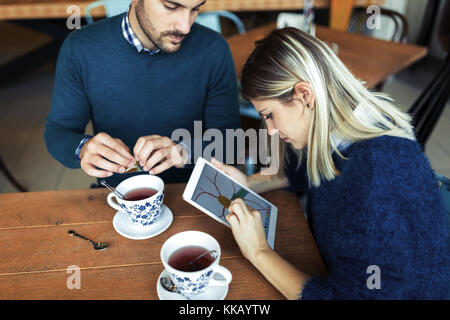 Giovane coppia attraente utilizzando tablet in coffee shop Foto Stock