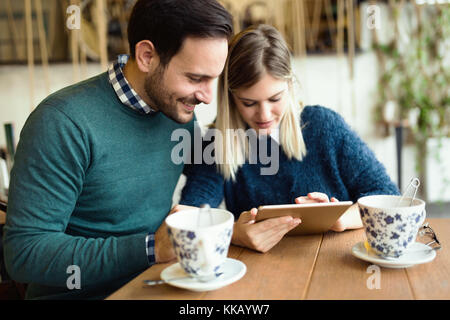 Giovane coppia attraente utilizzando tablet in coffee shop Foto Stock