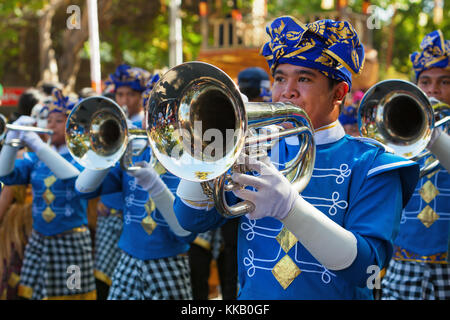 DENPASAR, ISOLA DI BALI, INDONESIA - 13 GIUGNO 2015: Gruppo di persone balinesi. Gli uomini della banda di ottoni marciano per strada in città e suonano musica al festival artistico Foto Stock