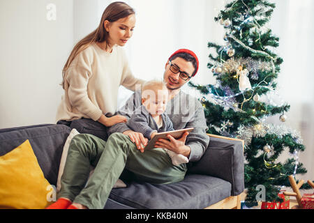 Famiglia seduto in soggiorno divertendosi con tablet pc che Babbo Natale ha portato Foto Stock