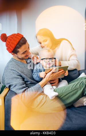 Famiglia seduto in soggiorno divertendosi con tablet pc che Babbo Natale ha portato Foto Stock