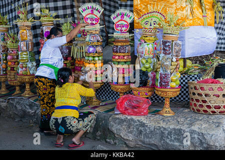 Donne indonesiane preparare offerte / gebogans per cerimonia al grande banyan tree sull'isola Nusa Lembongan vicino a Bali, in Indonesia Foto Stock