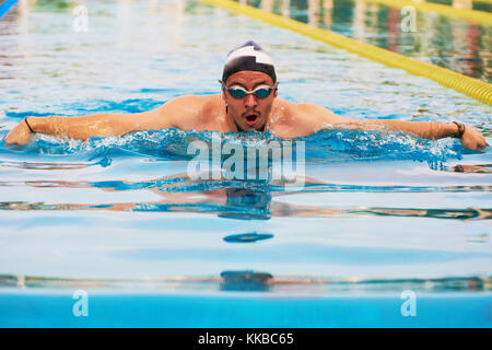 Close-up del nuotatore uomo in blu piscina esterna di acqua Foto Stock