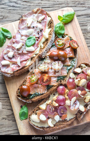 Bruschetta con diversi condimenti sul pannello di legno Foto Stock