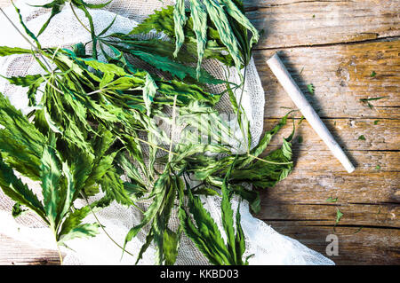 Essiccata la marijuana di foglie e un giunto su una tavola di legno Foto Stock