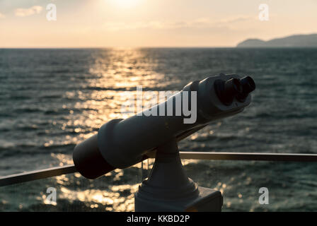 Binocolo contro il tramonto al mare Foto Stock