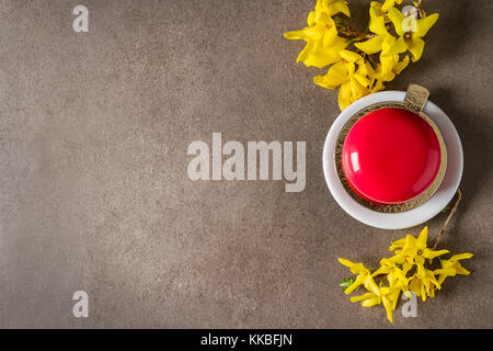Mousse di moda la torta con una glassa a specchio decorato con fiori di primavera. sfondo scuro. Foto Stock
