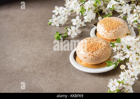 Mousse di moda la torta con una glassa a specchio decorato con fiori di primavera. sfondo scuro. Foto Stock