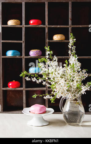 Mousse di moda la torta con una glassa a specchio decorato con fiori di primavera. sfondo scuro. Foto Stock