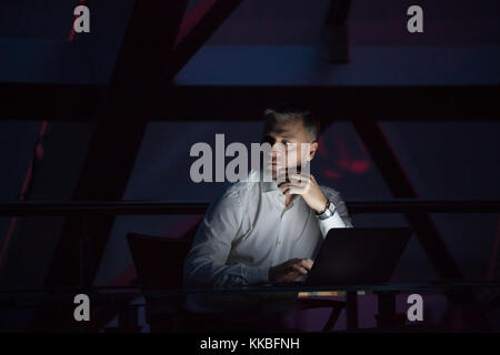 Imprenditore lavorando sul computer portatile in ufficio di notte. Foto Stock