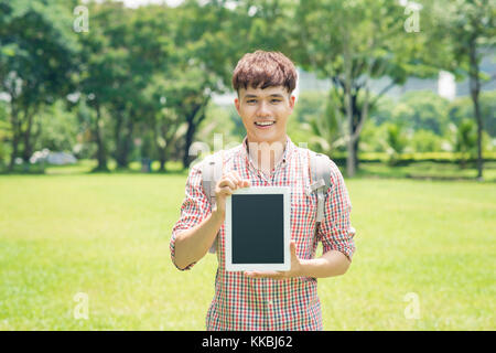 Allegro Giovane Uomo in camicia a scacchi puntando sulla schermata vuota tablet all'aperto Foto Stock