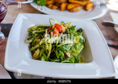 Insalata fresca con lattuga, cetriolo, pomodoro, rucola in bianco ciotola. Concetto di cibo sano Foto Stock