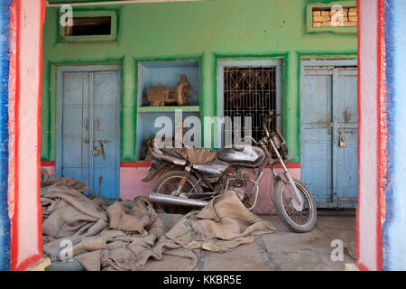 Una moto al di fuori di un dipinto luminosamente shop in un villaggio vicino a Bijaipur, Rajasthan, India Foto Stock