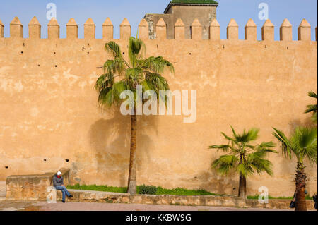 Uomo seduto vicino a una città fortificata a parete Foto Stock