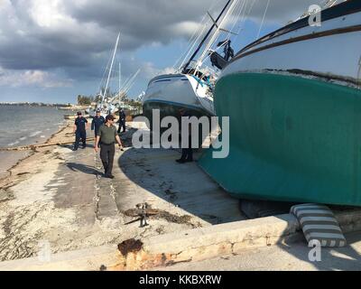 Gli ufficiali della Guardia Costiera degli Stati Uniti ispezionano le barche a vela danneggiate lavate a riva presso la Naval Air Station Key West Trumbo Point Annex durante gli sforzi di soccorso in seguito all'uragano Irma, 15 settembre 2017, a Key West, Florida. (Foto di Christopher M. Yaw via Planetpix) Foto Stock