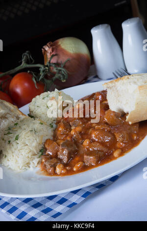 Una piastra di tradizionali turchi fagioli in umido, Etli kuru fasulye, con Orzo Riso pilaf e crosta di pane. Foto Stock