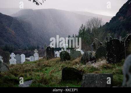 Cimitero con vecchie lapidi in valle inferiore al sito monastico di Glendalough, Co. Wicklow, Irlanda Foto Stock
