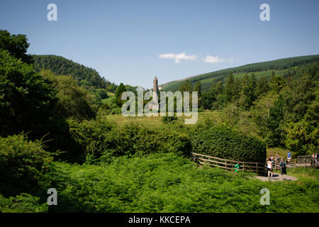 I turisti in visita nella bellissima glendalough bassa valle con vista su un sito monastico con torre rotonda. wicklow Mountain National Park, Irlanda Foto Stock